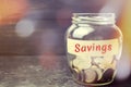 Glass jar with coins and the inscription `Savings`. The concept of accumulating money in the family budget. Family Insurance. Dist