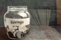 Glass jar with coins and the inscription `Savings`. The concept of accumulating money in the family budget. Family Insurance. Dist