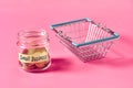 Glass jar with coins and inscription small business near empty market basket lies on pink Royalty Free Stock Photo