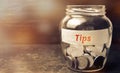 Glass jar with coins and the inscription ` Tips `. Award for good service in the cafe and restaurant. High level of service