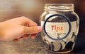 Glass jar with coins and the inscription ` Tips `. Award for good service in the cafe and restaurant. High level of service