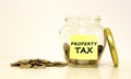 Glass jar with coins for savings. The inscription on the note paper PROPERTY TAX. Financial concept