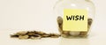Glass jar with coins for savings. The inscription on the note paper WISH. Financial concept