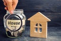 A glass jar with coins and a wooden house and the inscription `House`. The accumulation of money to buy a house. Rent an apartment Royalty Free Stock Photo