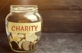 Glass jar with coins and the word Charity. The concept of accumulating money for donations. Saving. Social medical help from volun