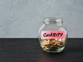 Glass jar with coins and the word charity on a label. Accumulating or saving money for donations, social solidarity and charitable Royalty Free Stock Photo