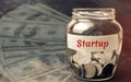 Glass jar with coins and the word ` Startup `. The concept of raising funds for a startup. Charitable contributions to translate i Royalty Free Stock Photo