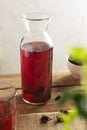 A glass jar with cold red hibiscus tea stands on a wooden table. Royalty Free Stock Photo