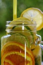 Glass jar with cold vitamin drink with sliced citrus fruits close-up.