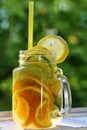 Glass jar with cold vitamin drink with sliced citrus fruits close-up.