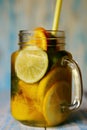Glass jar with cold, vitamin drink with sliced citrus fruits close-up.