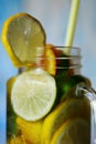 Glass jar with cold, vitamin drink with sliced citrus fruits close-up.