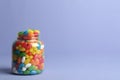 Glass jar with delicious bright jelly beans on color background Royalty Free Stock Photo