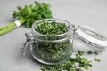 Glass jar with dried parsley on grey table Royalty Free Stock Photo