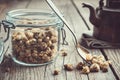 Glass jar of dry healthy chamomile buds, spoon and vintage teapot on old n wooden table. Royalty Free Stock Photo