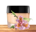 Glass jar of face cream and lilly flower on wooden table