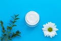 Glass jar of facial cream with white chamomile on blue background, skin care concept. Herbal lotion in bottle, natural cosmetic Royalty Free Stock Photo