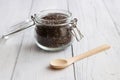 Glass jar filled with chia seeds and a nearby wooden spoon on a white old wooden table. Super food. Copy space Royalty Free Stock Photo