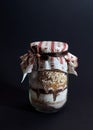 Glass jar filled with cookie baking mix, includes layers of cereal, flour, brown and white sugar and chocolate powder, covered