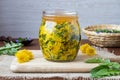 A glass jar filled with dandelion flowers and honey