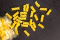 Glass jar filled with dry pasta spiral fusilli and scattered around on black background Royalty Free Stock Photo