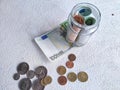 Glass Jar Filled With Euro Banknotes and Coins on Table. Concept of savings ranging from small money to large Royalty Free Stock Photo