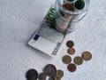 Glass Jar Filled With Euro Banknotes and Coins on Table. Concept of savings ranging from small money to large Royalty Free Stock Photo