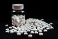 A glass jar filled with white pills is placed on top of a table, White medical pills or tablets with bottle on black background, Royalty Free Stock Photo