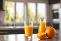 Glass and jar of fresh orange juice with oranges on wooden table, kitchen background. Royalty Free Stock Photo