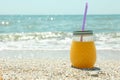 Glass jar of fresh orange juice on seaside, space for text. Summer vacation Royalty Free Stock Photo