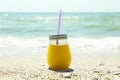 Glass jar of fresh orange juice on seaside, space for text. Summer vacation Royalty Free Stock Photo