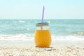 Glass jar of fresh orange juice on seaside, space for text. Summer vacation Royalty Free Stock Photo