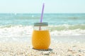 Glass jar of fresh orange juice on seaside, space for text. Summer vacation Royalty Free Stock Photo