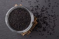 Glass jar full of black cumin seeds over black background. Macro. Cooking with nigella seeds concept. Kalonji as spice and Royalty Free Stock Photo