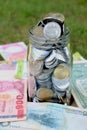 Glass jar full of coins on different currency note Royalty Free Stock Photo