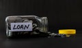 Glass jar full of coins fallen on ground with yellow cap, black background and LOAN label Royalty Free Stock Photo