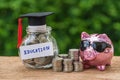 glass jar with full of coins and graduates hat label with Piggybank and stack of coins as Education, education or savings concept Royalty Free Stock Photo