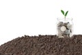 A glass jar with full coins and plant growing on top with soil to show concept saving money, land and house Royalty Free Stock Photo