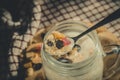 Glass jar with a healthy breakfast of oatmeal with nuts, dried fruits and yogurt. Early morning, top view, close up