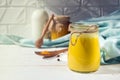 Glass jar with a healthy drink of golden milk made from turmeric, milk and pepper on a white wooden background. Royalty Free Stock Photo