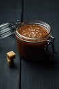 A glass jar with homemade salted caramel and a few pieces of brown sugar Royalty Free Stock Photo