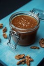Glass jar of homemade salted caramel and fried walnuts on a blue board Royalty Free Stock Photo