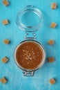 A glass jar of homemade salted caramel with pieces of cane sugar Royalty Free Stock Photo