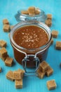 A glass jar of homemade salted caramel with pieces of cane sugar Royalty Free Stock Photo