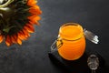 Glass jar with honey on black background. Liquid honey. Sunflower flower. Bio product. Glass stick for honey. View from Royalty Free Stock Photo