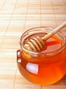 Glass jar of honey with wooden drizzler