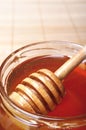 Glass jar of honey with wooden drizzler