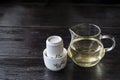 Glass jar of hot tea and set of white ceramic cups