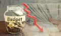 Glass jar and the inscription ` Budget ` and down arrow. Unsuccessful business and poverty. Profit decline. Loss of investment. Lo Royalty Free Stock Photo