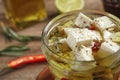 Glass jar of marinated feta cheese on wooden table, closeup Royalty Free Stock Photo